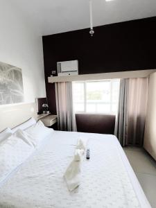 um quarto com uma cama branca com um controlo remoto em San Marino Residences em Cebu