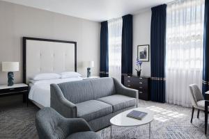 ein Schlafzimmer mit einem Bett, einem Sofa und einem Stuhl in der Unterkunft London Marriott Hotel Grosvenor Square in London