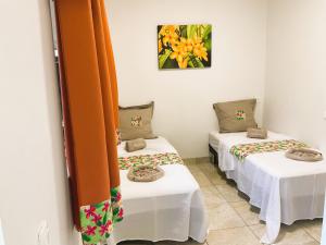 2 łóżka w pokoju z pomarańczowymi zasłonami w obiekcie RURUTU - Are Itimaana Fare w Rurutu