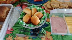 a table with a bowl of bread and a plate of buns at Mansão de Pirah Suites in Niterói