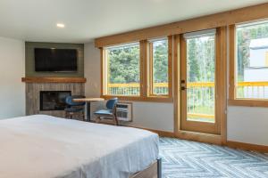 a bedroom with a bed and a fireplace and windows at Hotel Canoe and Suites in Banff