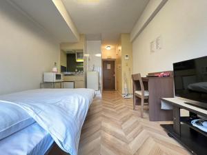 a bedroom with a bed and a kitchen with a desk at A&C STAY Shin Osaka Higashiguchi 82 in Osaka