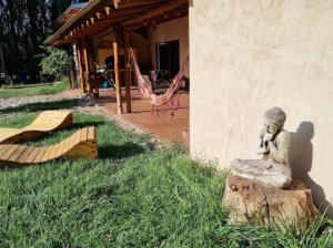 una estatua de una mujer sentada en un muñón en el césped en La Posada de Buda en Malargüe