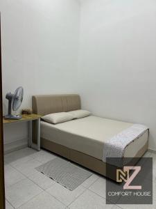 a bedroom with a bed and a desk with a lamp at Nz comfort house pandan kuantan in Kuantan