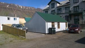 a building with cars parked in front of a house at Comfortable Bungalow in Ísafjörður