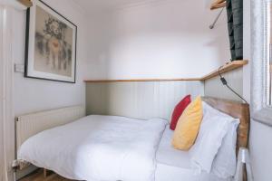 Dormitorio pequeño con cama con sábanas y almohadas blancas en Vibrant & Eclectic 3 bedroom Flat - Bedminster Bristol! en Bristol