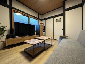a living room with a couch and a flat screen tv at TasoneUrbanStayOsaka 梅田中津2 in Osaka