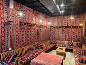 a room with wooden benches in a room with red wallpaper at Hotel Seever in Erbil