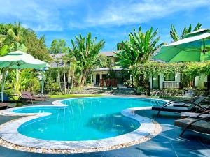 Una piscina con sillas y sombrillas al lado de una casa. en Rum Resort Phu Quoc, en Phu Quoc