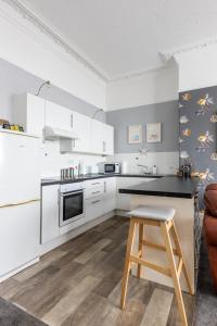 a kitchen with white cabinets and a stool in it at Beach Shore - SEA VIEWS in Lytham St Annes