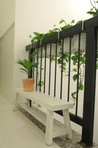 HOTEL VĂN THÁI BÌNH في Trà Vinh: مقاعد بيضاء عليها نباتات على الحائط