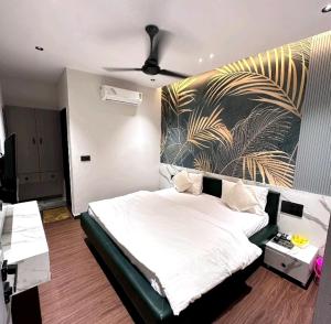 um quarto com uma cama branca e uma pintura tropical na parede em V Love Hotel em Surate