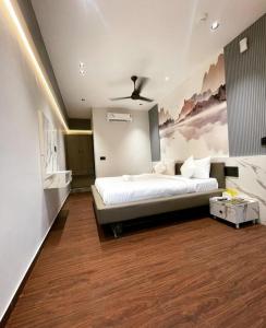 1 dormitorio con 1 cama y una pintura en la pared en V Love Hotel en Surat