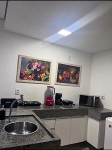 a kitchen with two paintings on the wall and a sink at Flat Paiva Home Stay in Recife