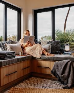 una mujer sentada en un sofá leyendo un libro en Ecopia Retreat en Seal Bay