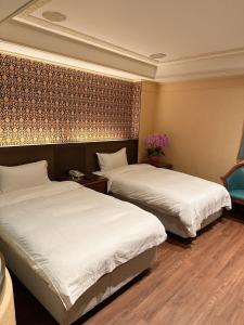 Habitación de hotel con 2 camas con sábanas blancas en Duke Business Hotel en Taoyuan