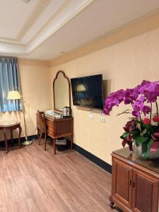 una camera d'albergo con tavolo e TV di Duke Business Hotel a Taoyuan