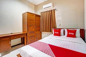 een slaapkamer met een bed met rode kussens en een bureau bij OYO 90889 Dkb Residence in Surabaya