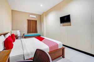 1 dormitorio con 1 cama y TV en la pared en OYO 90889 Dkb Residence, en Surabaya
