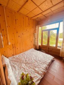 a bed in a wooden room with a window at Lâm Bích Homestay & Coffee in Ấp Phước Thánh