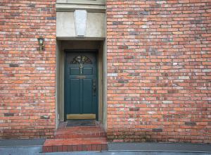 a green door on a brick building with a sidewalk at Historic Townhouse in Kitsilano in Vancouver