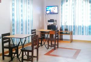 a dining room with two tables and chairs and a television at RedDoorz @ D'Little Egg Hostel Pangasinan in Urdaneta