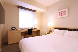 Habitación de hotel con cama, escritorio y ventana en KOKO HOTEL Sendai Station West en Sendai