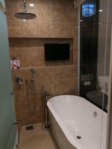 a bathroom with a bath tub and a tv on the wall at Dorsett Bukit Bintang Pavilion in Kuala Lumpur