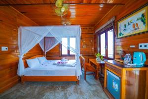 ein Schlafzimmer mit einem Himmelbett und einem Schreibtisch in der Unterkunft Jungle Boss Travel Lodge in Phong Nha