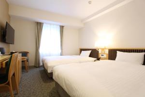 a hotel room with two beds and a desk at KOKO HOTEL Sendai Station South in Sendai