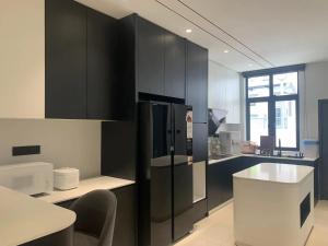 a kitchen with black cabinets and a refrigerator at Luxe J Homestay in Taiping