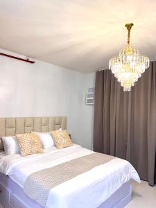 um quarto com uma cama e um lustre em Cozy Condo Unit in Puerto Princesa City near PPS Airport em Puerto Princesa