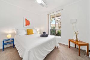 een witte slaapkamer met een groot wit bed en een raam bij Sunset Soirée - WiFi Beach Family in Sellicks Beach