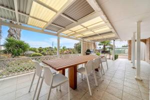 een patio met een houten tafel en stoelen bij Sunset Soirée - WiFi Beach Family in Sellicks Beach