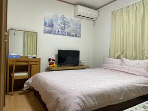 um quarto com uma cama, uma secretária e uma televisão em 東京田園平安旅館 em Kawaguchi