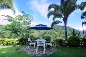 a table and chairs with an umbrella and palm trees at Estate Bungalow in Ratnapura
