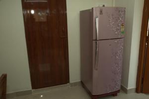 a purple refrigerator in a room next to a wooden door at IZI APOLLO STAY in Chennai