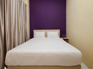 a bedroom with a white bed with a purple wall at RAP Hotel Balige in Balige