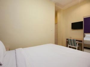 um quarto com uma cama branca e uma cadeira em RAP Hotel Balige em Balige