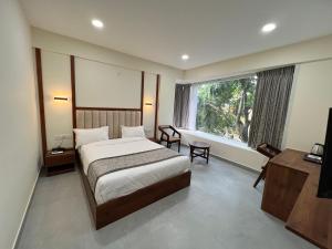 Vrishi Inn في بانغالور: غرفه فندقيه بسرير ونافذه