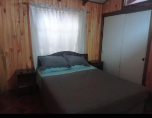 een slaapkamer met een bed met een raam en een gordijn bij Espacio Indómito in Purén