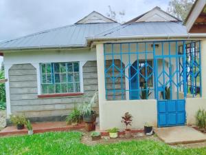ein Haus mit einer blauen Tür und Fenstern in der Unterkunft BONNY KINGs FARMSTAY in Kiambu