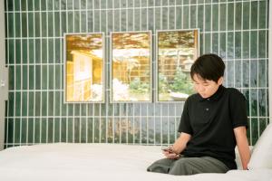 a young boy sitting on a bed looking at a cell phone at Asakusa 1976 in Tokyo