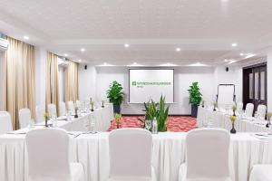 a conference room with white tables and chairs and a screen at Wyndham Garden Hoi An Cua Dai Beach in Hoi An