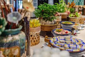 a table with plates of food and plants in baskets at Wyndham Garden Hoi An Cua Dai Beach in Hoi An