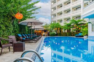 a pool at a hotel with chairs and an umbrella at Wyndham Garden Hoi An Cua Dai Beach in Hoi An