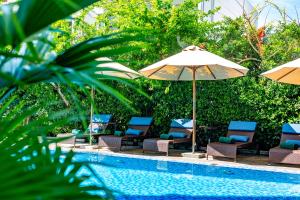 a group of chairs and umbrellas next to a pool at Wyndham Garden Hoi An Cua Dai Beach in Hoi An