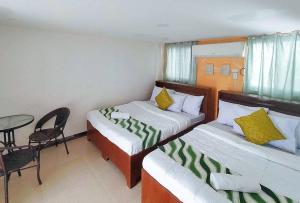 Habitación de hotel con 2 camas, mesa y silla en RedDoorz @ Recson Hostel Coron Palawan, en Corón