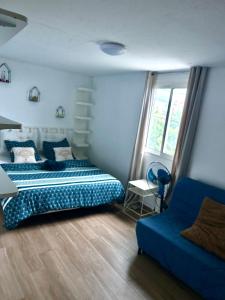 a bedroom with a blue bed and a blue couch at Maison vue mer chaleureuse et confortable in Petite Île