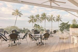 a patio with tables and chairs and palm trees at Crystalbrook Flynn in Cairns